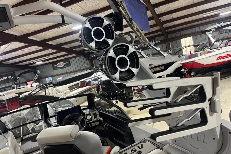 Slide: The Image of 2021 Malibu Wakesetter 25 LSV interior with speakers and wakeboard racks in showroom. - 11