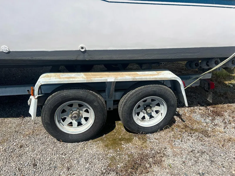Slide: The Image of 1987 Grady-White Seafarer 226 boat on a dual-axle trailer, parked on gravel. - 3