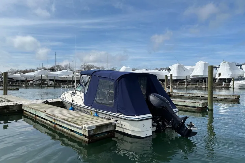 Slide: The Image of 2002 Arima Sea Ranger 21 Hardtop docked at marina, featuring blue canopy and outboard motor. - 10