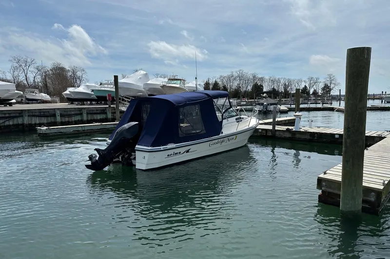 Slide: The Image of 2002 Arima Sea Ranger 21 Hardtop boat docked in a marina under a cloudy sky. - 12