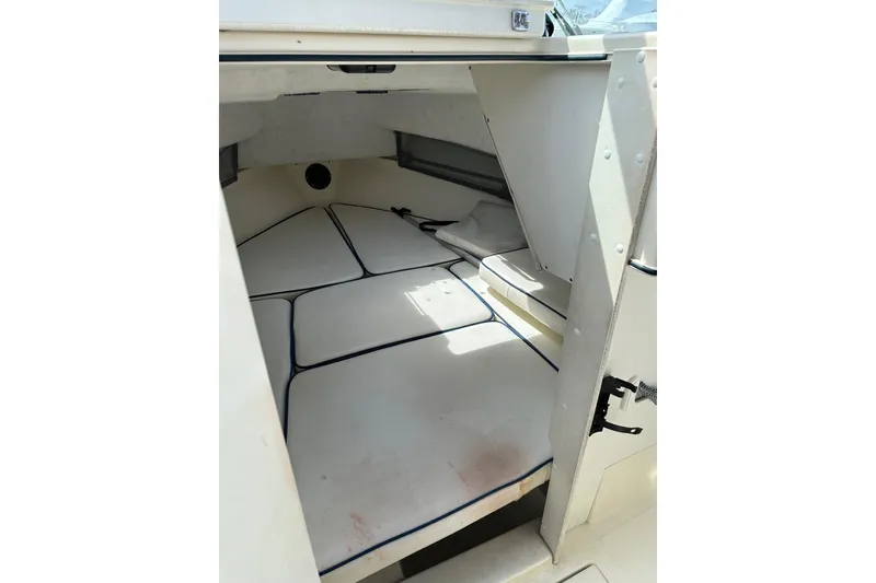 Slide: The Image of 2002 Arima Sea Ranger 21 Hardtop cabin interior with cushioned seating and storage space. - 3