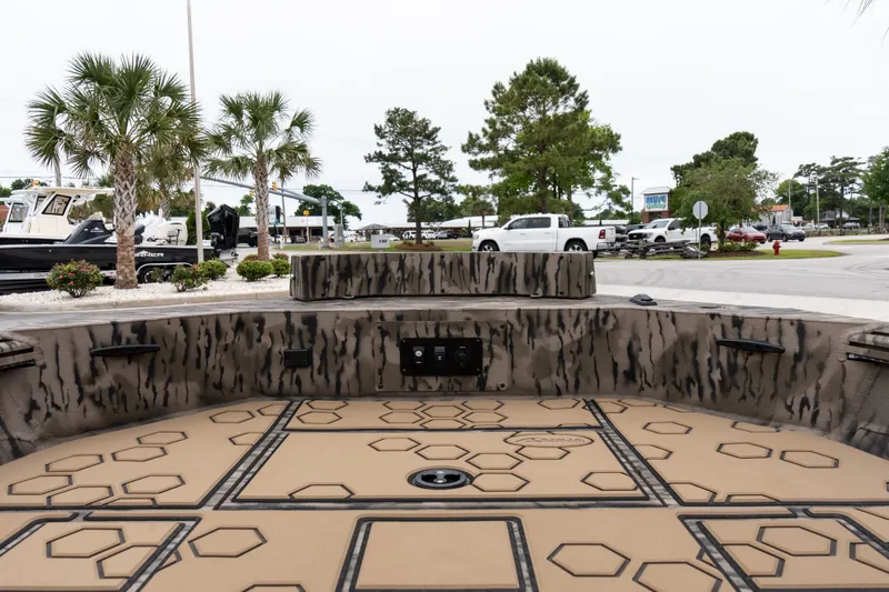 Slide: The Image of 2026 Excel 183 Tomahawk boat interior with camouflage design, parked near palm trees and vehicles. - 9