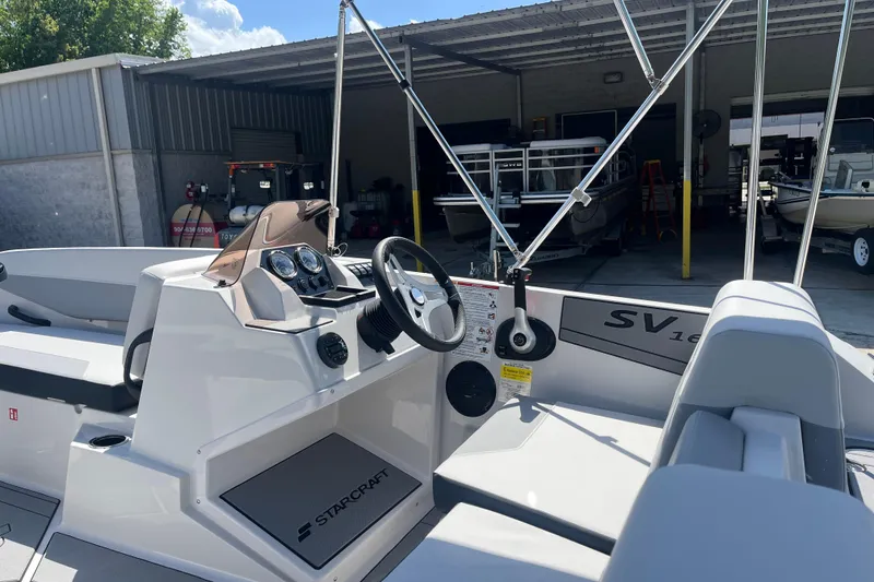 Slide: The Image of 2026 Starcraft SV 16 OB boat interior with steering wheel and dashboard in a showroom. - 13