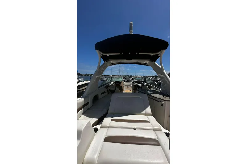 Slide: The Image of 2015 Chaparral 264 Sunesta boat interior with seating and helm, docked under clear blue sky. - 21