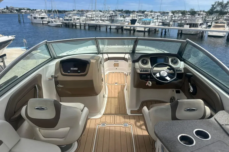 Slide: The Image of 2015 Chaparral 264 Sunesta boat interior with steering wheel, seating, and docked marina view. - 24
