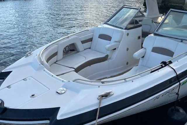 Slide: The Image of 2015 Chaparral 264 Sunesta boat with spacious seating, docked on calm water. - 4