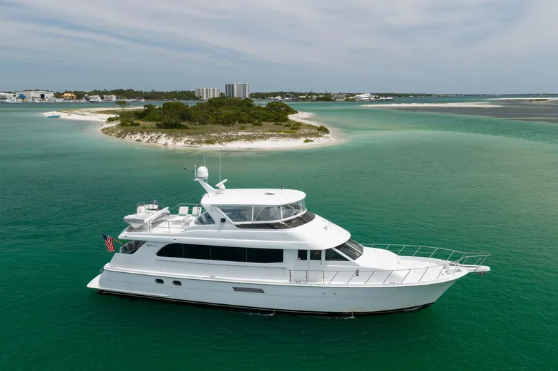 The Image of 2004 Hatteras 75 Sport Deck Motor Yacht cruising near a scenic island. - 1