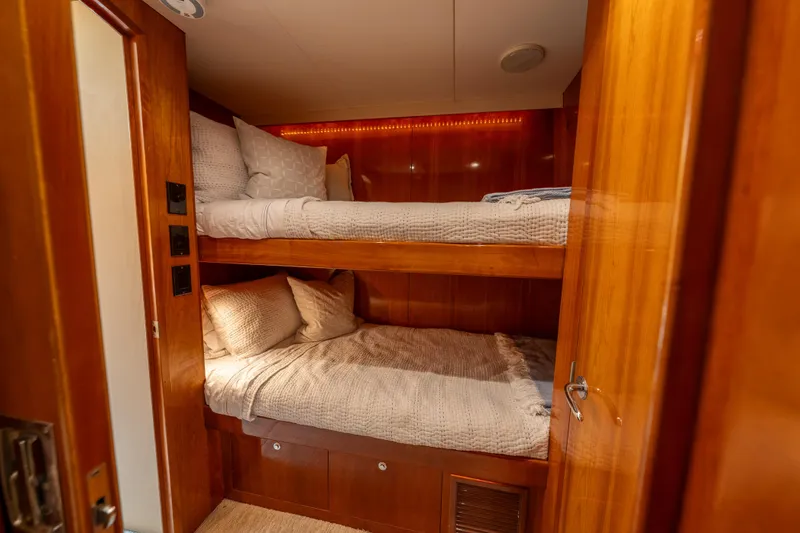 Slide: The Image of Bunk beds in 2004 Hatteras 75 Sport Deck Motor Yacht cabin, featuring wood paneling and cozy bedding. - 26