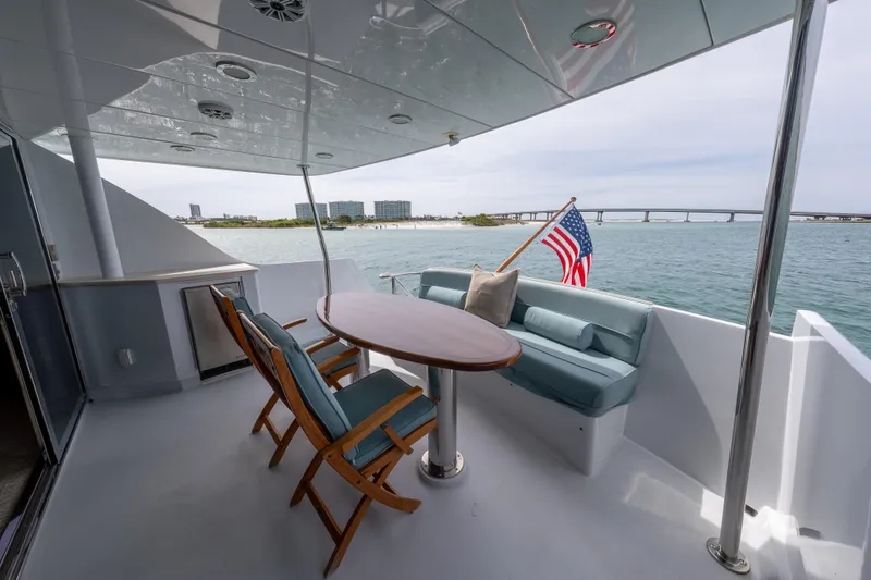 Slide: The Image of 2004 Hatteras 75 Sport Deck Motor Yacht deck with seating, table, and American flag. - 42