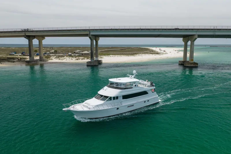 Slide: The Image of 2004 Hatteras 75 Sport Deck Motor Yacht cruising under a bridge in clear turquoise waters. - 54