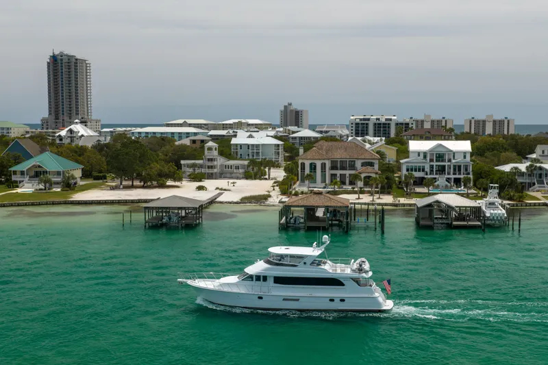 Slide: The Image of 2004 Hatteras 75 Sport Deck Motor Yacht cruising near waterfront homes and docks. - 55