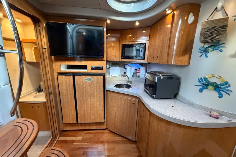 Slide: The Image of 2002 Regal Commodore 3860 yacht interior with kitchenette, TV, and wooden cabinetry. - 25