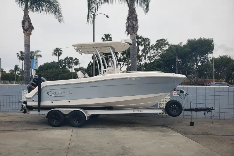 The Image of 2020 Robalo R222 Explorer boat on trailer, parked near palm trees. - 0
