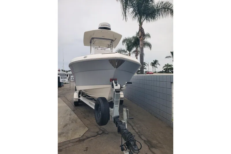 Slide: The Image of 2020 Robalo R222 Explorer boat on trailer, parked near palm trees. - 2