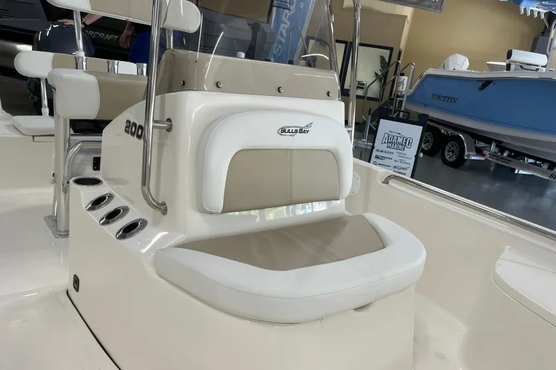 Slide: The Image of 2026 Bulls Bay 2000 boat interior with seating and console, displayed in a showroom. - 21