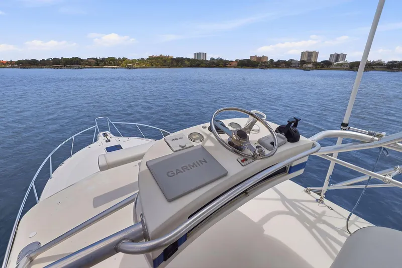 Slide: The Image of 2005 Rampage 38 Express boat helm with Garmin navigation, overlooking calm waters and distant shoreline. - 23