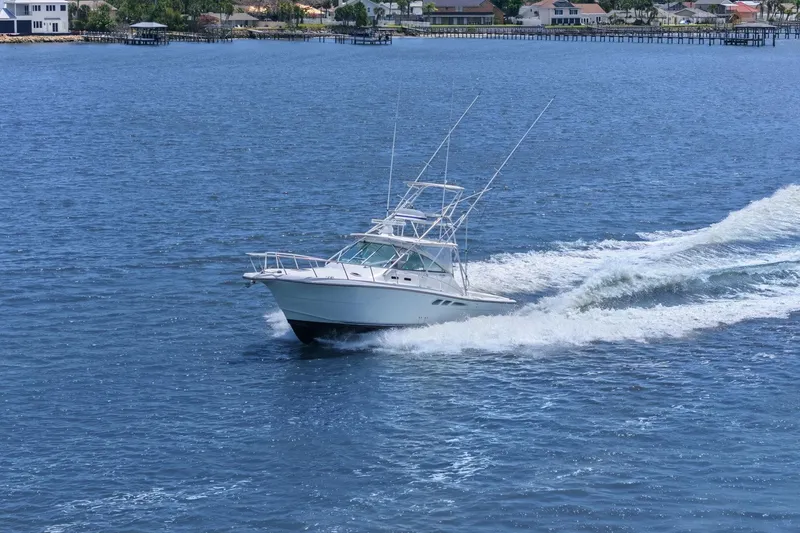 Slide: The Image of 2005 Rampage 38 Express boat cruising on open water near coastal homes. - 3
