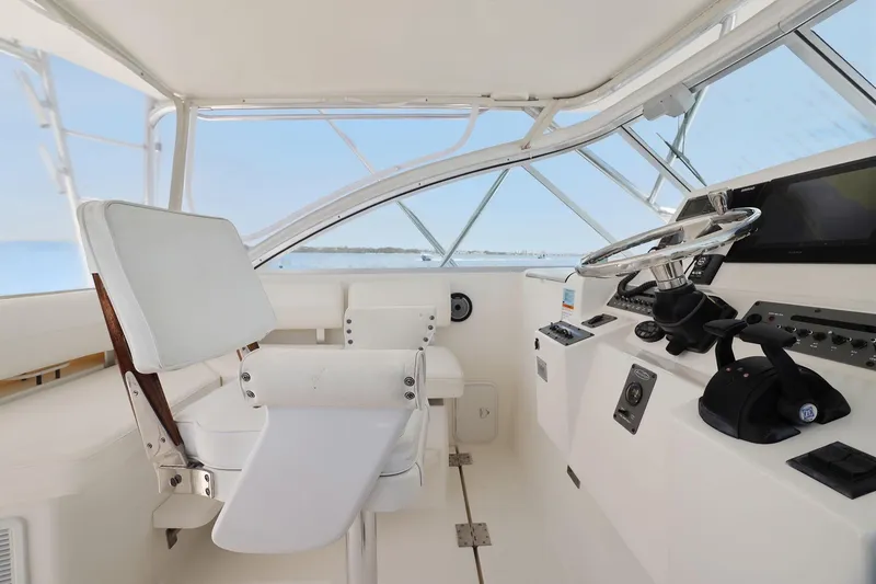 Slide: The Image of 2005 Rampage 38 Express boat cockpit with steering wheel and white seating. - 30