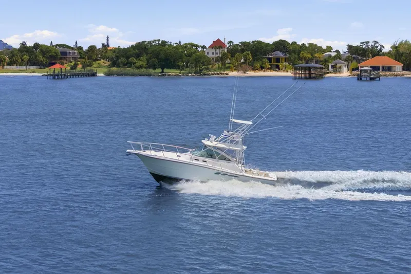Slide: The Image of 2005 Rampage 38 Express boat cruising on a scenic lake with waterfront homes. - 4