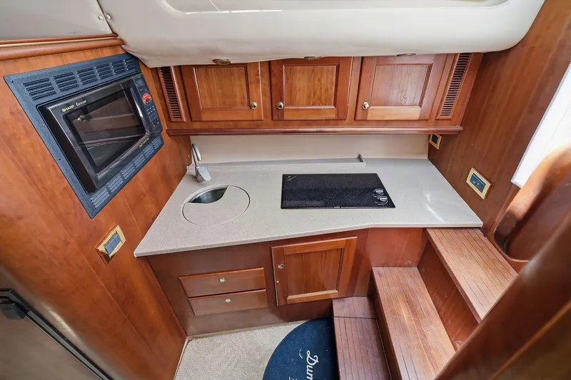 Slide: The Image of 2005 Rampage 38 Express yacht kitchen with microwave, sink, and wooden cabinetry. - 49