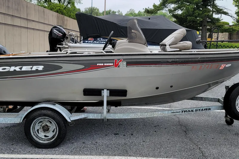 The Image of 2004 Tracker Pro Deep V-16 Single Console boat on a trailer in a parking lot. - 0