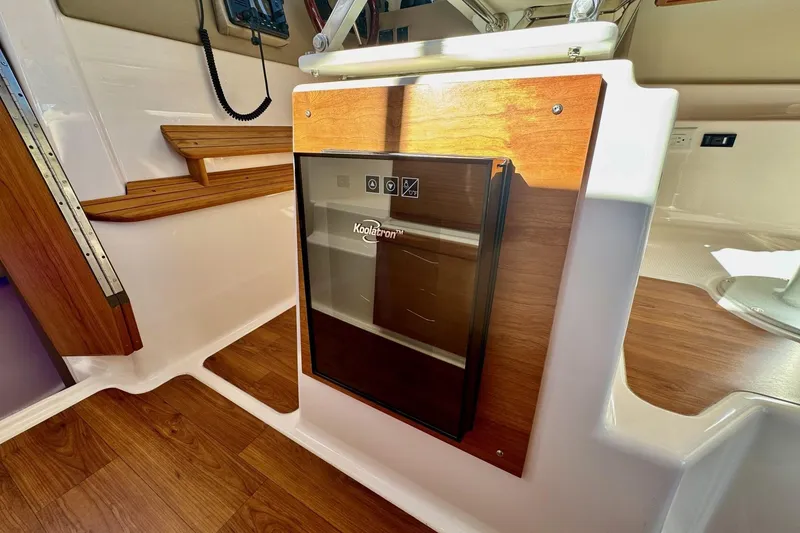 Slide: The Image of Interior of 2022 Cutwater C-32 CB boat with wooden flooring and compact fridge. - 10