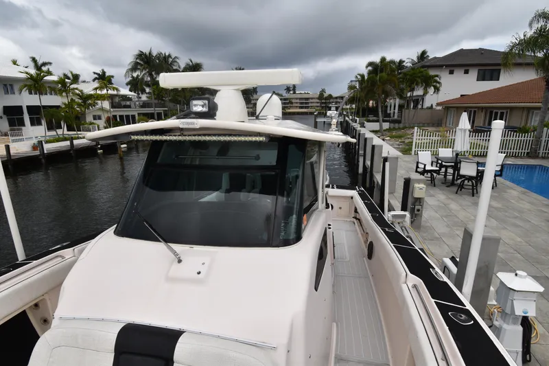 Slide: The Image of 2010 Grady-White Canyon 366 boat docked near waterfront homes under cloudy skies. - 12
