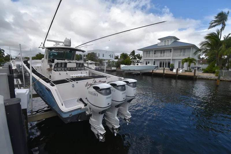 Slide: The Image of 2010 Grady-White Canyon 366 boat docked by waterfront home, featuring triple Suzuki engines. - 18