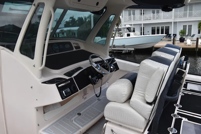 Slide: The Image of 2010 Grady-White Canyon 366 boat interior with helm and seating, docked near waterfront homes. - 21