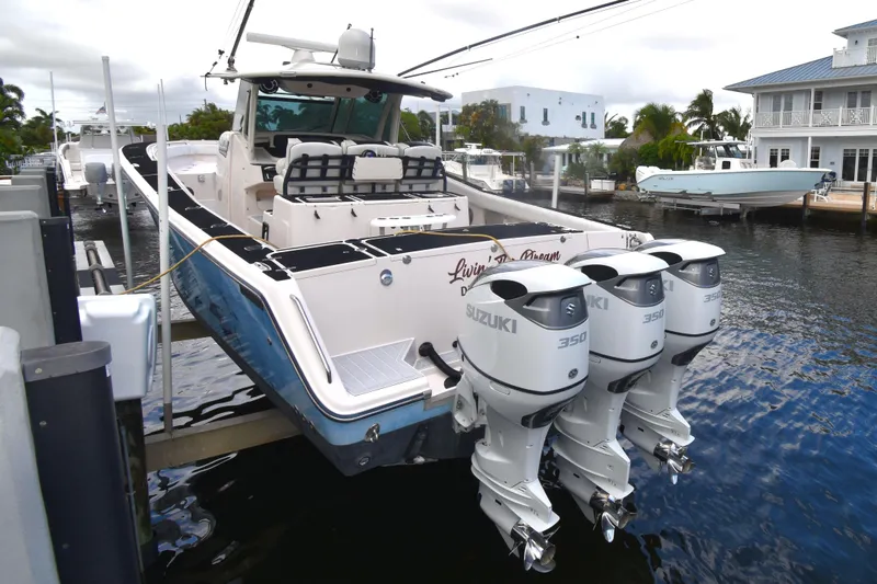Slide: The Image of 2010 Grady-White Canyon 366 boat docked by waterfront home, featuring triple Suzuki engines. - 26