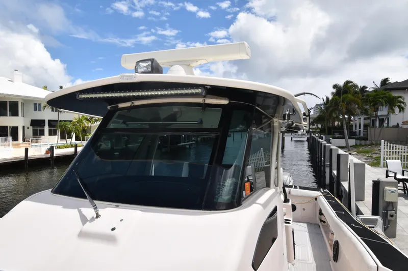 Slide: The Image of 2010 Grady-White Canyon 366 boat docked by waterfront homes under a cloudy sky. - 7