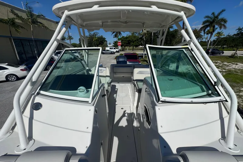 Slide: The Image of 2023 Sailfish 245 DC boat with open cockpit and windshield, parked outdoors. - 16
