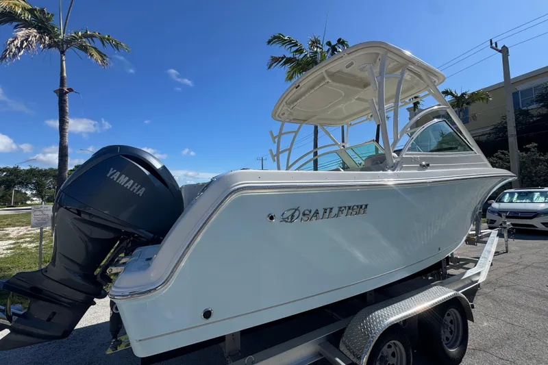 Slide: The Image of 2023 Sailfish 245 DC boat on trailer with Yamaha engine, under clear blue sky. - 2