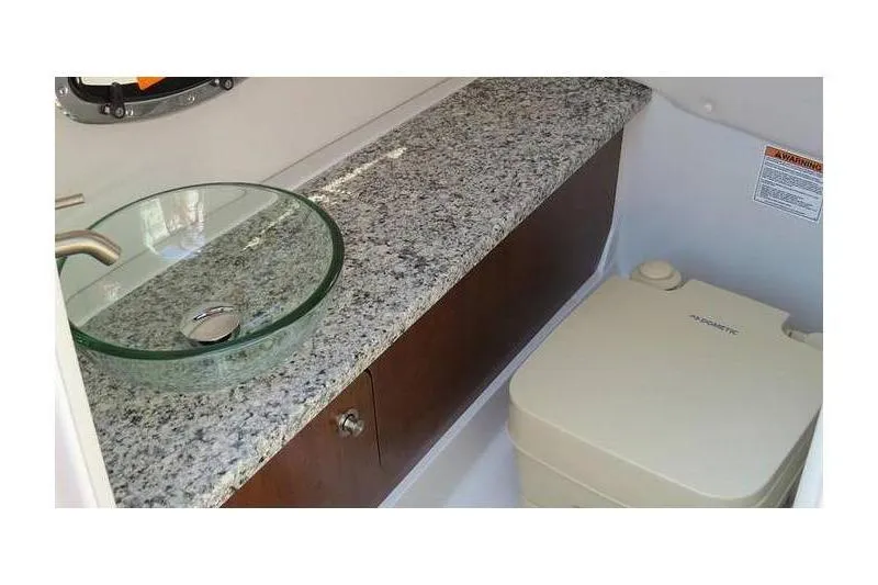 Slide: The Image of 2024 Crownline 250 XSS boat interior with granite countertop and glass sink. - 10