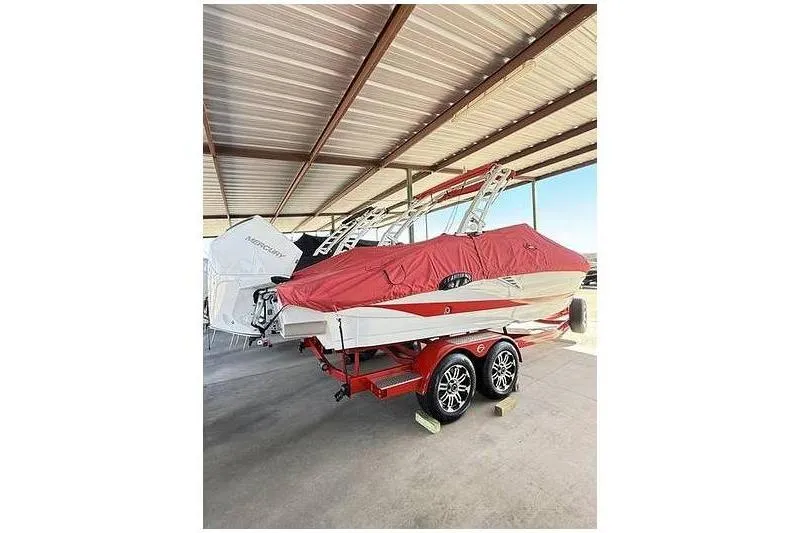 Slide: The Image of 2024 Crownline 250 XSS boat with red cover on trailer in covered storage. - 4