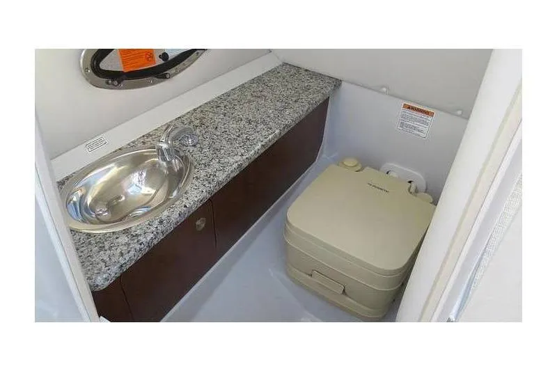 Slide: The Image of 2024 Crownline 250 XSS boat interior with sink and portable toilet. - 9