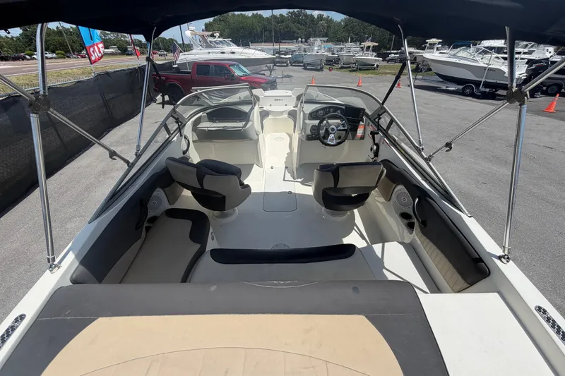 Slide: The Image of 2018 Stingray 204 LR boat interior with seating and steering wheel, displayed outdoors. - 12