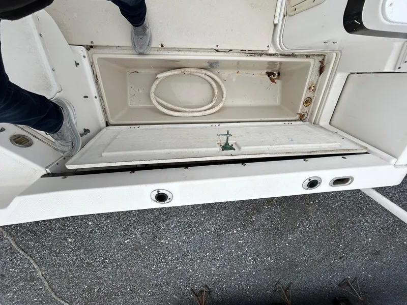 Slide: The Image of 1996 Robalo 2440 Walkaround boat deck with open storage compartment and coiled rope. - 12