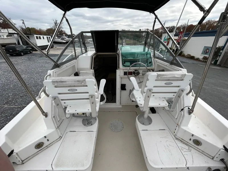 Slide: The Image of 1996 Robalo 2440 Walkaround boat interior with dual white captain chairs and steering console. - 13
