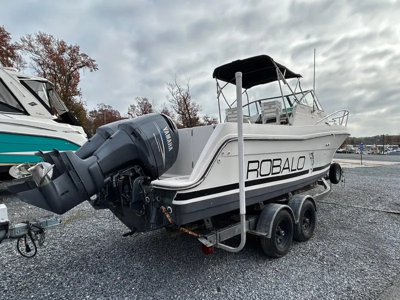 Slide: The Image of 1996 Robalo 2440 Walkaround boat on trailer with Yamaha outboard motor, parked on gravel. - 4