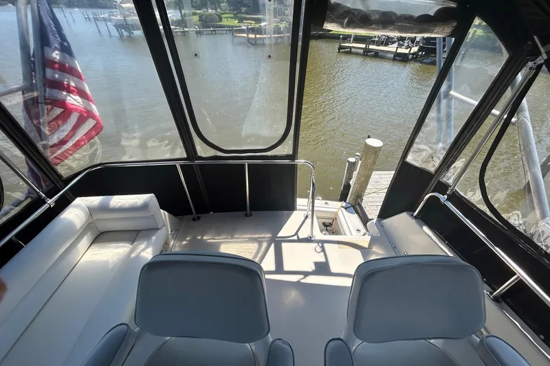 Slide: The Image of 1990 Silverton 34 Convertible boat interior with seating, docked by a serene waterfront. - 17