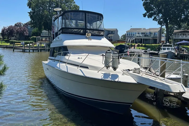 Slide: The Image of 1990 Silverton 34 Convertible yacht docked in a scenic marina setting. - 2