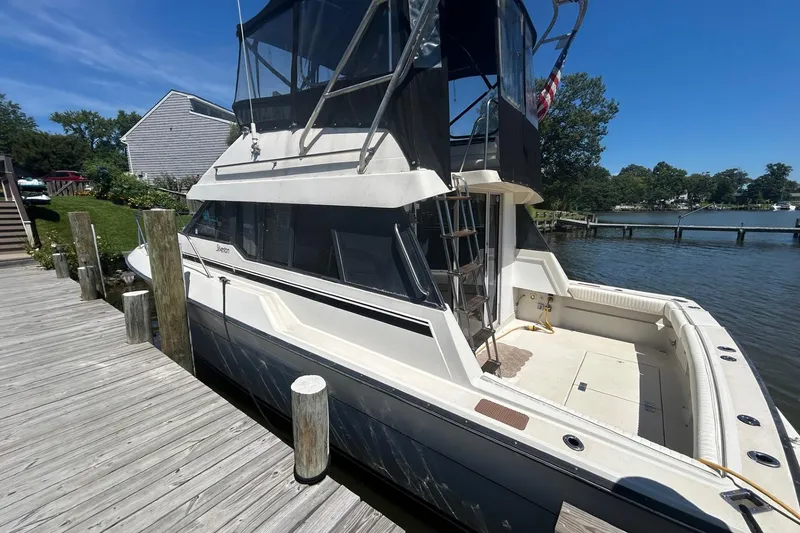 Slide: The Image of 1990 Silverton 34 Convertible docked by a wooden pier on a sunny day. - 3