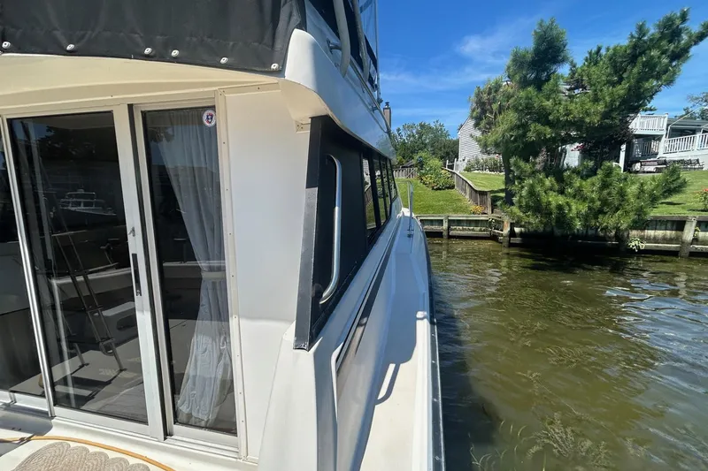 Slide: The Image of 1990 Silverton 34 Convertible yacht docked by a lush, green waterfront. - 8