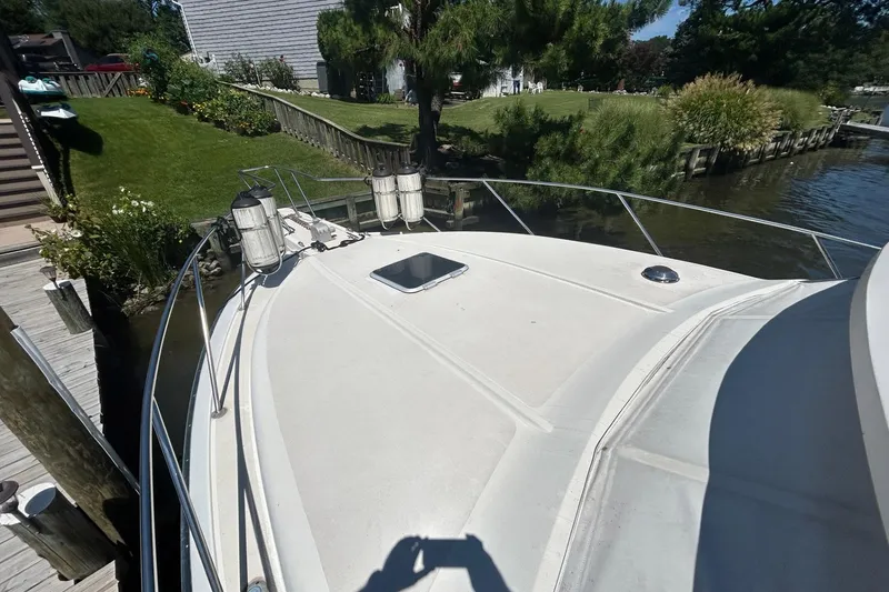 Slide: The Image of 1990 Silverton 34 Convertible boat docked by a lush, green riverside. - 32