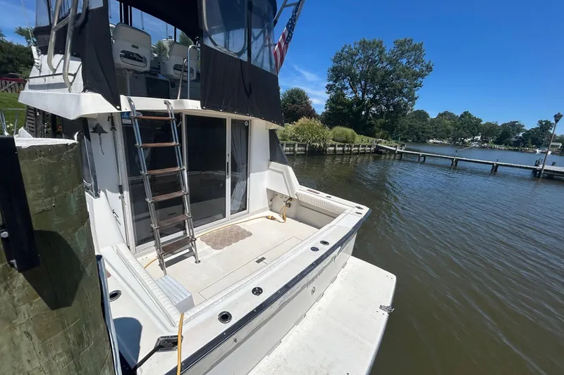Slide: The Image of 1990 Silverton 34 Convertible boat docked by a scenic waterfront with clear blue skies. - 6