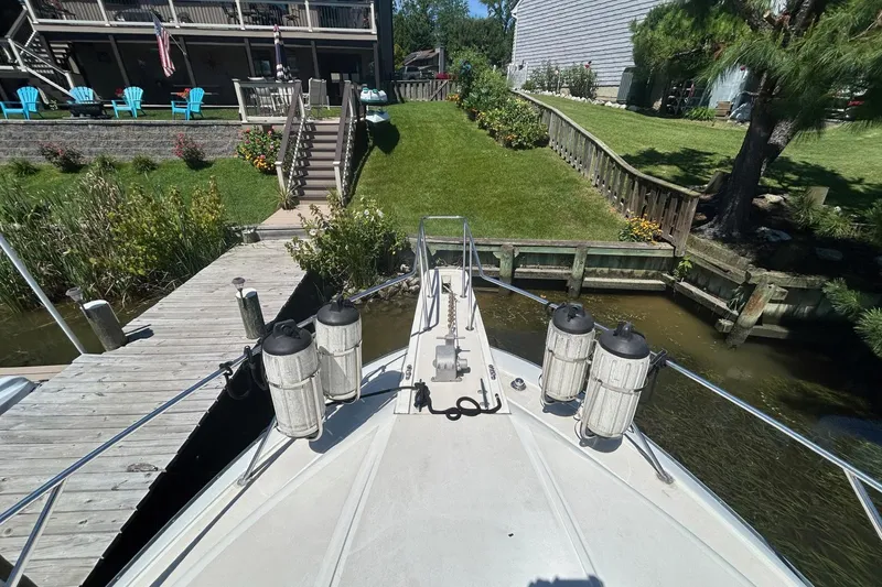 Slide: The Image of Bow view of 1990 Silverton 34 Convertible docked near a lush garden. - 33