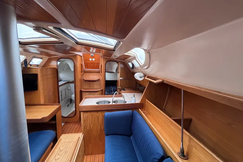 Slide: The Image of Interior of 1990 Beneteau Oceanis 350 sailboat with wood finish and blue seating. - 14