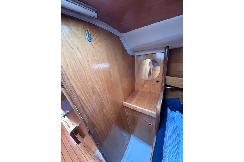 Slide: The Image of Interior of 1990 Beneteau Oceanis 350 sailboat with wooden cabinetry and round mirror. - 27