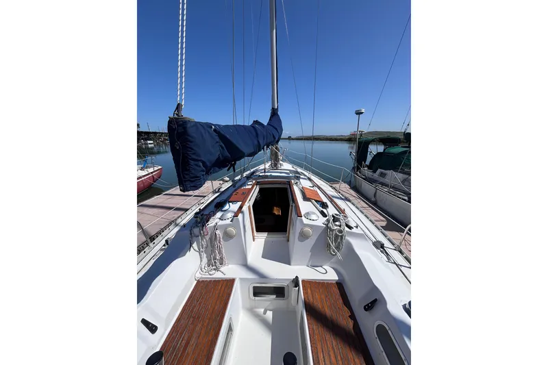 Slide: The Image of 1990 Beneteau Oceanis 350 sailboat docked, showcasing deck and mast under clear blue sky. - 3